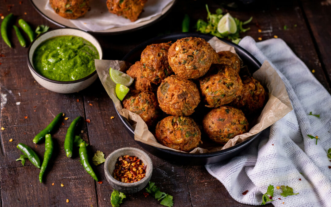 Polpette in un piatto circondato da vari condimenti.